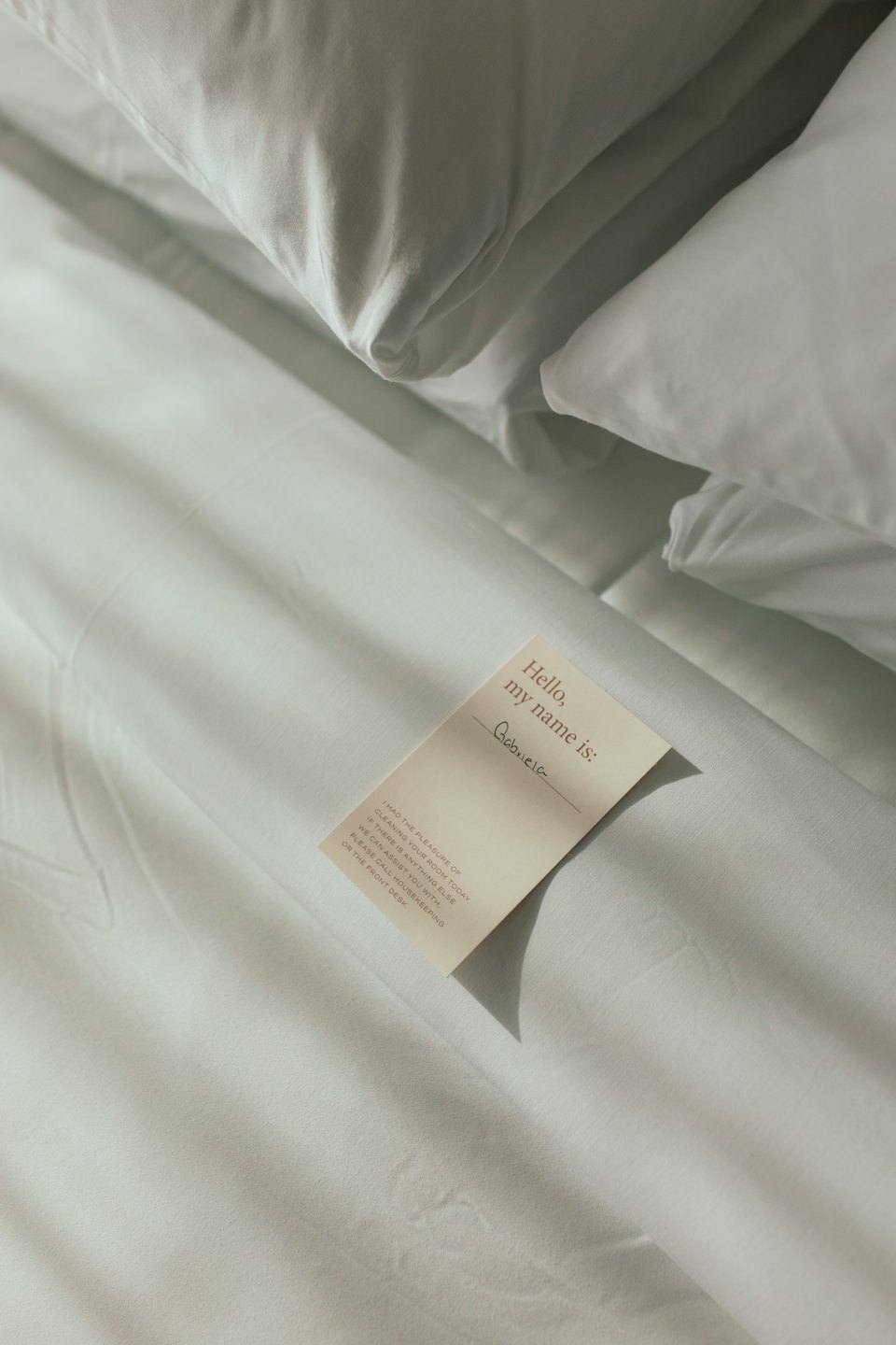 Hotel bed with a housekeeper's note on the duvet.